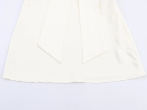 Detailopname van de crème satijnen mini-jurk met elegante decoratieve sjaalachtige linten