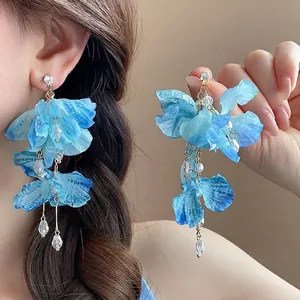 Detailed close-up of blue fabric flower earrings with crystal beads and long chain tassels