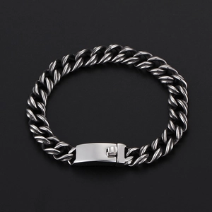 Detail view of silver Cuban chain bracelet with rectangular buckle on black background