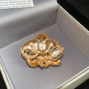 Detailed macro view of orchid flower brooch in polished gold on gray velvet box