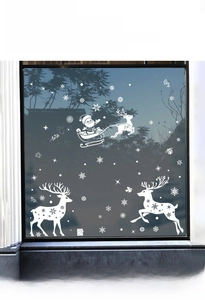 Close-up of white Christmas window decals featuring Santa's sleigh, reindeer, and snowflakes