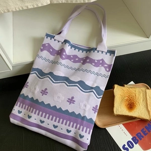 Detail of purple knitted tote bag showing intricate wave, heart, and geometric patterns