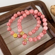 Macro detail of pink beaded bracelets with golden flower charms and natural stone texture