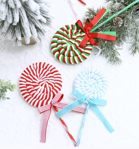 Detail of plush Christmas lollipop ornaments with striped bows on festive pine branches