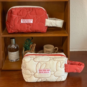Quilted cotton rabbit makeup bag with wrist strap and stay cute slogan on wooden shelf
