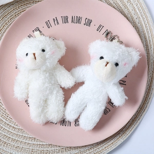 Close-up of two white plush teddy bear pendants with pink blush and silver bead chains