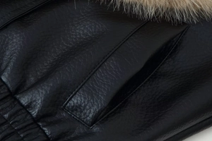 Close-up of black leather jacket texture with plush faux fur collar and pocket stitching