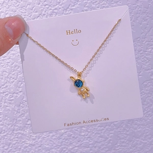 Dettaglio ravvicinato di una collana con ciondolo a coniglio dorato e sfera cosmica blu