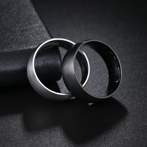 Macro detail of 8mm brushed stainless steel rings in matte silver and black finishes