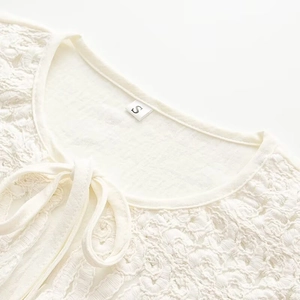 Detailed close-up of white lace blouse neckline with elegant bow tie and embroidery texture