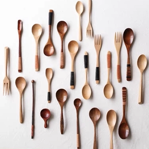 Flat lay of assorted wooden spoons and forks with woven handles on white background