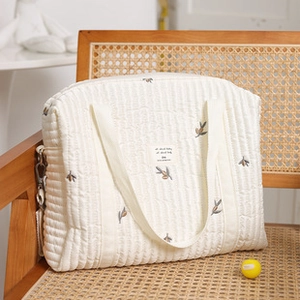 Detalle de un bolso tote infantil de lona acolchada blanca con bordado floral de olivo