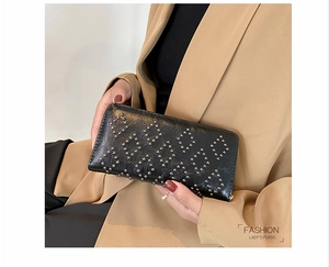 Detail einer schwarzen Lederclutch mit silbernen Nieten und goldenem Reißverschluss