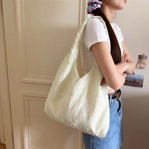 Nahaufnahme der floralen Stickerei auf einer hellgrünen Canvas-Schultertasche