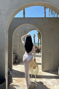 Vue arrière d'une robe de plage en maille blanche à manches longues sur fond de vacances