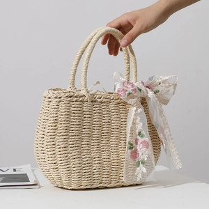 Handheld beige woven straw handbag featuring elegant pink floral lace ribbon decoration