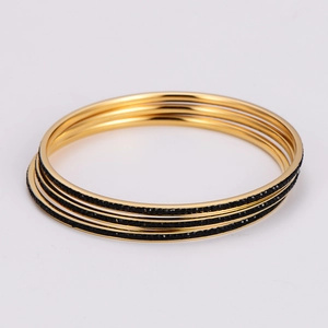 Close-up of three stacked gold stainless steel bracelets with black crystal inlay