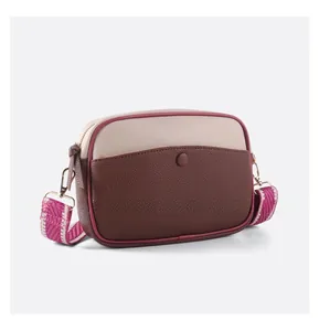 Détail du sac bandoulière bicolore avec texture grainée et bandoulière en jacquard tissé