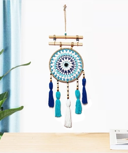 Detailed view of woven cotton tassels and blue evil eye pattern on a wooden wall hanging