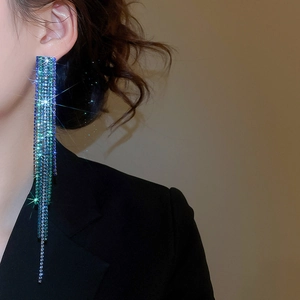 Close-up of sparkling aurora tassel earrings with blue-green rhinestones on model