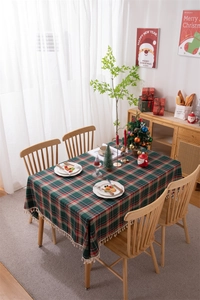 Detailed view of red and green plaid Christmas tablecloth with decorative tassel edges