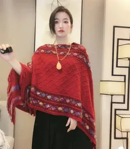 Close-up of red knit poncho with ethnic geometric jacquard and fringe hem details