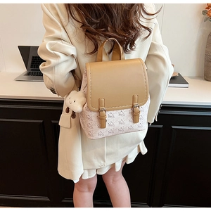 Détail d'un sac à dos beige et marron avec motifs de dessins animés et pendentif peluche