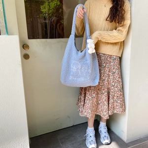 Detail of sky blue fleece tote bag featuring Snoopy embroidery and a plush bear charm