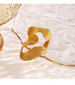 Close-up of sculptural golden ring with irregular wavy lines and metallic texture