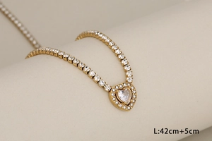 Macro shot of 42cm gold tennis necklace with paved heart pendant on a display stand