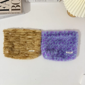 Plush animal print makeup bags in brown stripe and purple patterns on a cream table