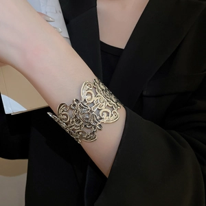 Detail of vintage hollow flower wide cuff bracelet in gold finish on black suit