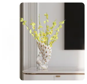 Detail of elegant white ceramic peacock vase with gold accents and yellow faux flowers