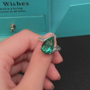 Macro detail of pear-cut Paraiba tourmaline ring with pavé diamonds in silver finish