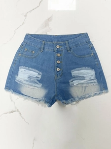 Detail of high waisted blue denim shorts featuring four-button fly and distressed frayed hem