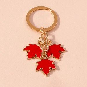 Detailed close-up of golden keychain featuring three vibrant red maple leaf charms