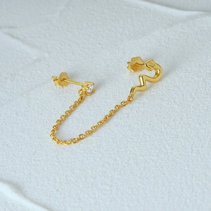 Detailed macro view of S925 sterling silver gold snake earring with chain and zircon stud