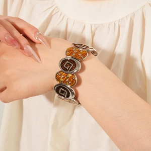 Détail du bracelet étoile en émail vintage avec motifs géométriques et zircons au poignet