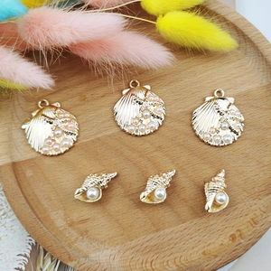 Set of gold shell and conch pendants with pearls and sea stars on a wooden tray