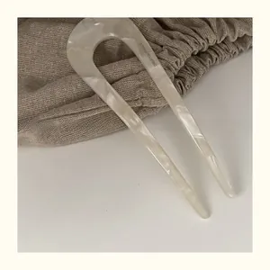 Detailed close-up of tortoise shell pattern acetate U-shaped hair pin with brand engraving
