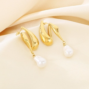 Detail of irregular gold metal earrings with white baroque pearl tassels on silk fabric