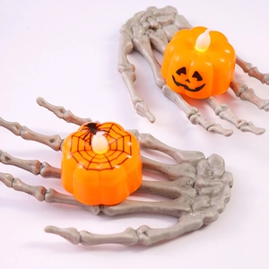 Dettaglio di candela LED a zucca di Halloween con supporto a mano di scheletro bianco
