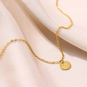 Vue macro du collier avec pendentif trèfle en plaqué or 18 carats sur satin champagne