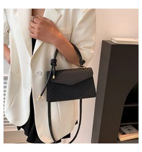 Detail of black woven texture on minimalist crossbody bag styled with white blazer