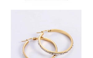 Macro view of gold-tone stainless steel hoop earrings with white rhinestone pavé setting