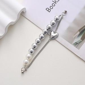 Silver bead bracelet with heart pendant and magnetic clasp on minimalist background