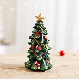 Miniature green resin Christmas tree with gold star and ornaments on wooden desk