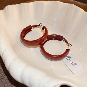 Vintage wine red enamel round stud earrings displayed on a white decorative shell tray