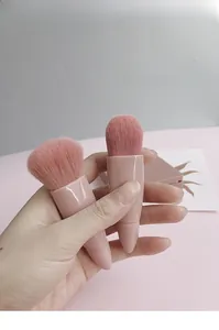 Detail view of two soft pink travel makeup brushes with ergonomic polished handles