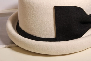 Detailed texture of ivory wool felt beret featuring an elegant black bow ribbon detail